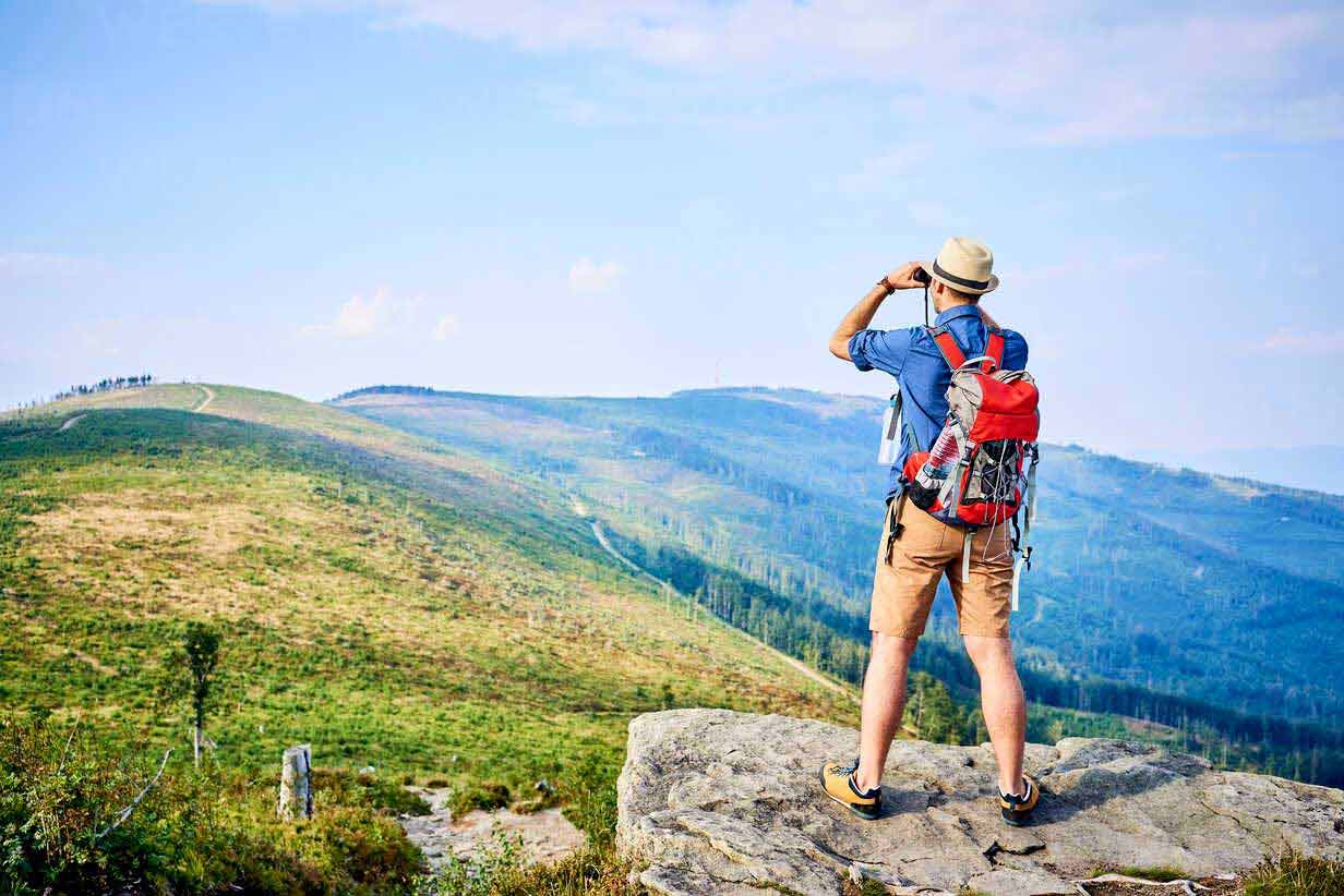 rear-view-of-man-looking-through-binoculars-during-hiking-trip-BSZF00706.jpg